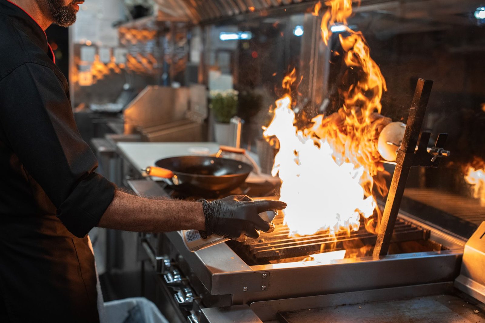 Professional grill restaurant interior with chef cooking at open flame kitchen, modern lighting and stainless steel equipment